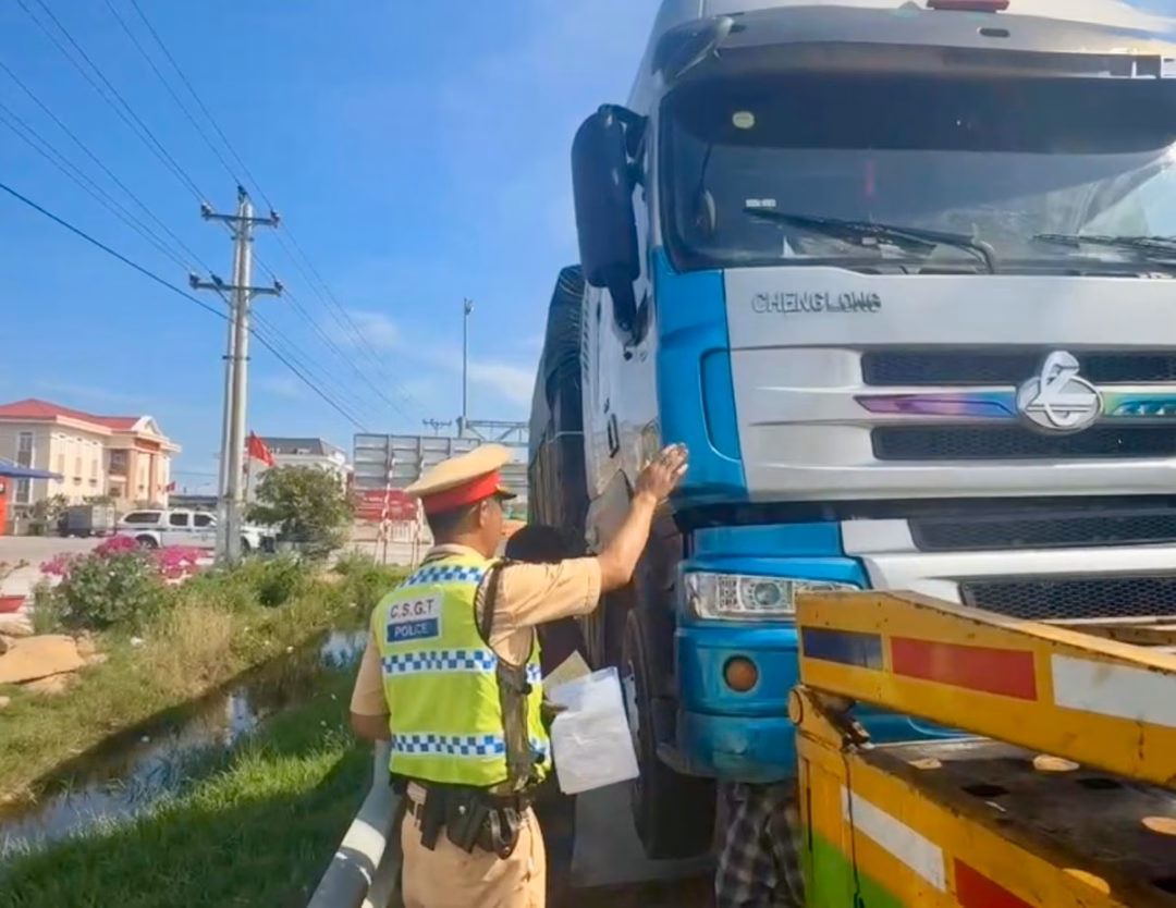 Lực lượng CSGT lập biên bản vi phạm đối với xe tải chở quá tải và tài xế không có giấy phép lái xe.